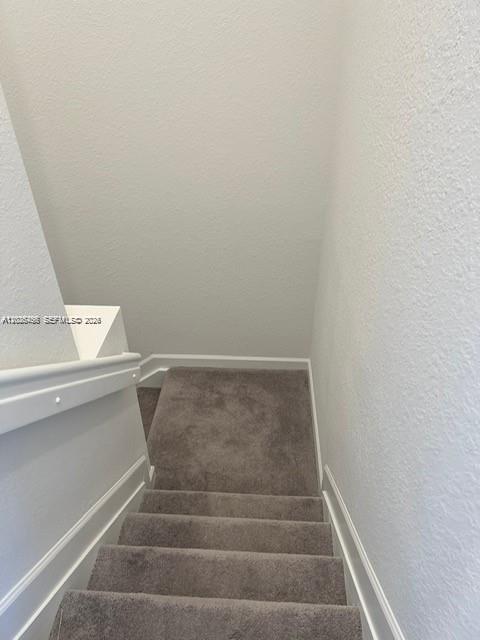 A view looking down a carpeted staircase with white walls and a white handrail — 12663 NW 24th Ave, Miami FL 33167, MIAMI, FL