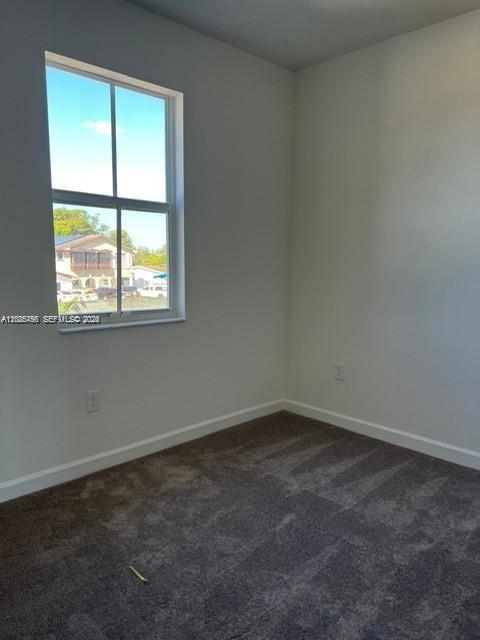 An empty bedroom features gray carpeting, white walls, and a window overlooking a residential street — 12663 NW 24th Ave, Miami FL 33167, MIAMI, FL