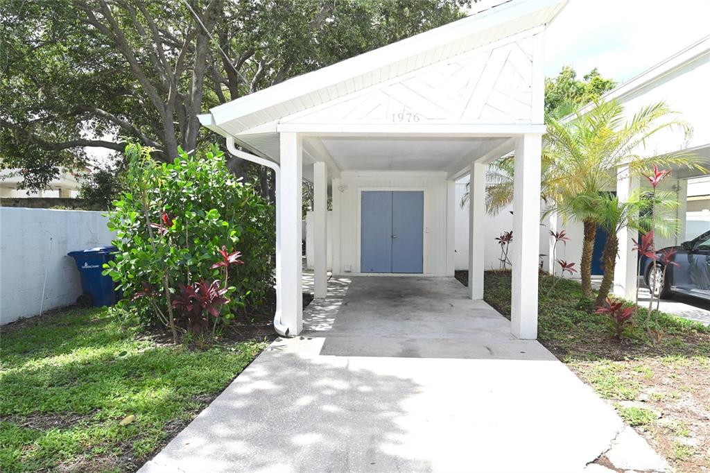 A white carport with a concrete driveway and blue double doors leads to a residence — 1976 DEBBIE STREET, SARASOTA, FL
