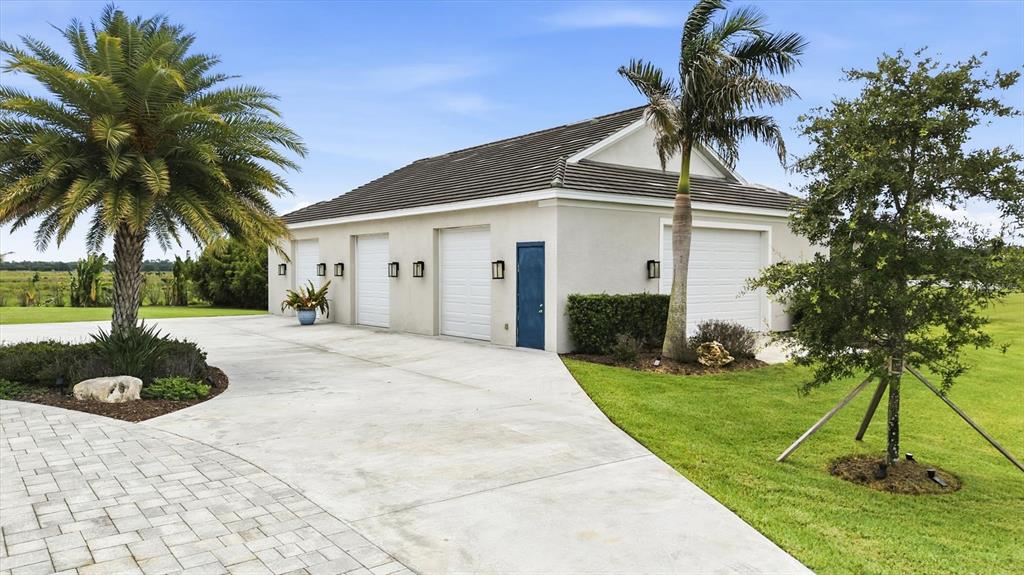 A detached garage with four white doors and a blue side door sits outdoors — 3467 COMPOUND COURT, SARASOTA, FL
