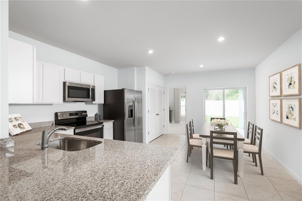 A kitchen with granite countertops and stainless steel appliances opens to a dining area — 6932 SUNDIAL DRIVE, LAKELAND, FL