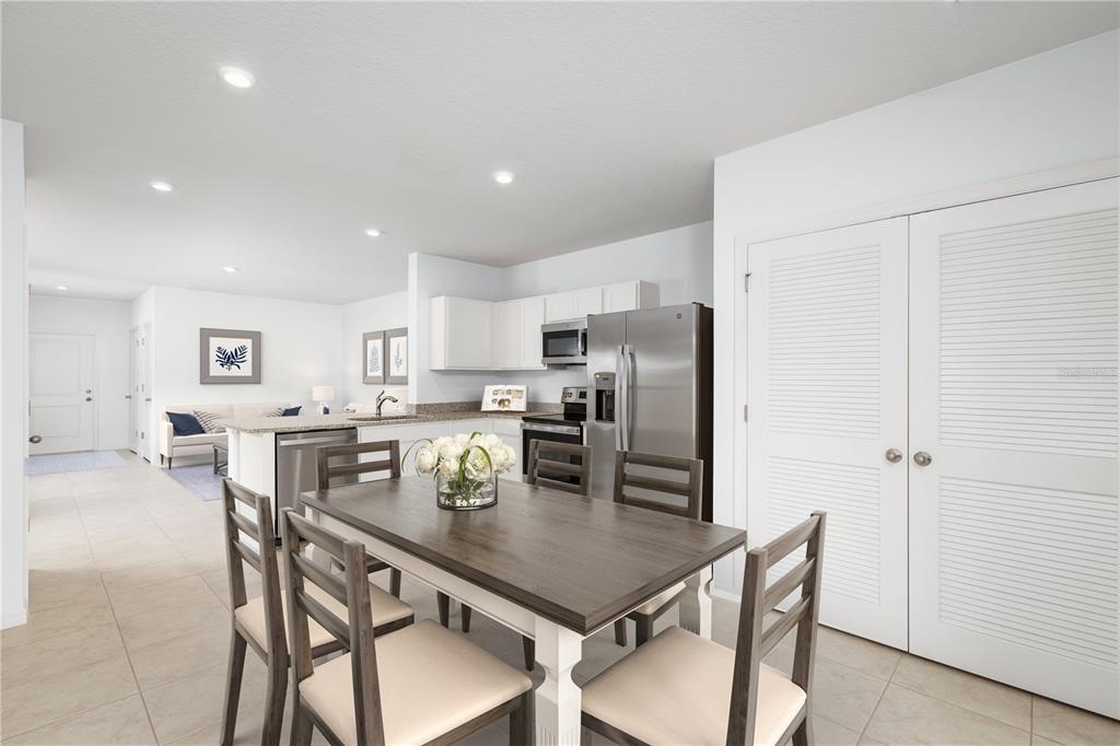 A dining area with a wooden table and chairs sits before an open-concept kitchen — 6932 SUNDIAL DRIVE, LAKELAND, FL