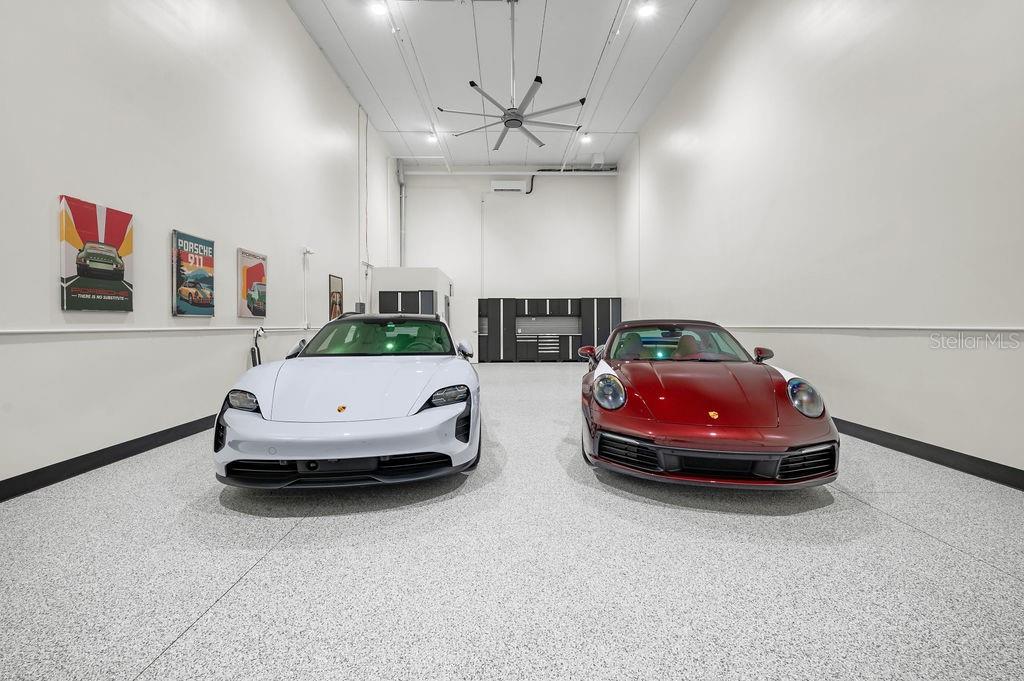 A spacious garage with white walls, a speckled floor, and two parked Porsche cars — 5431 COMMUNICATIONS PARKWAY UNIT 29, LAKEWOOD RANCH, FL