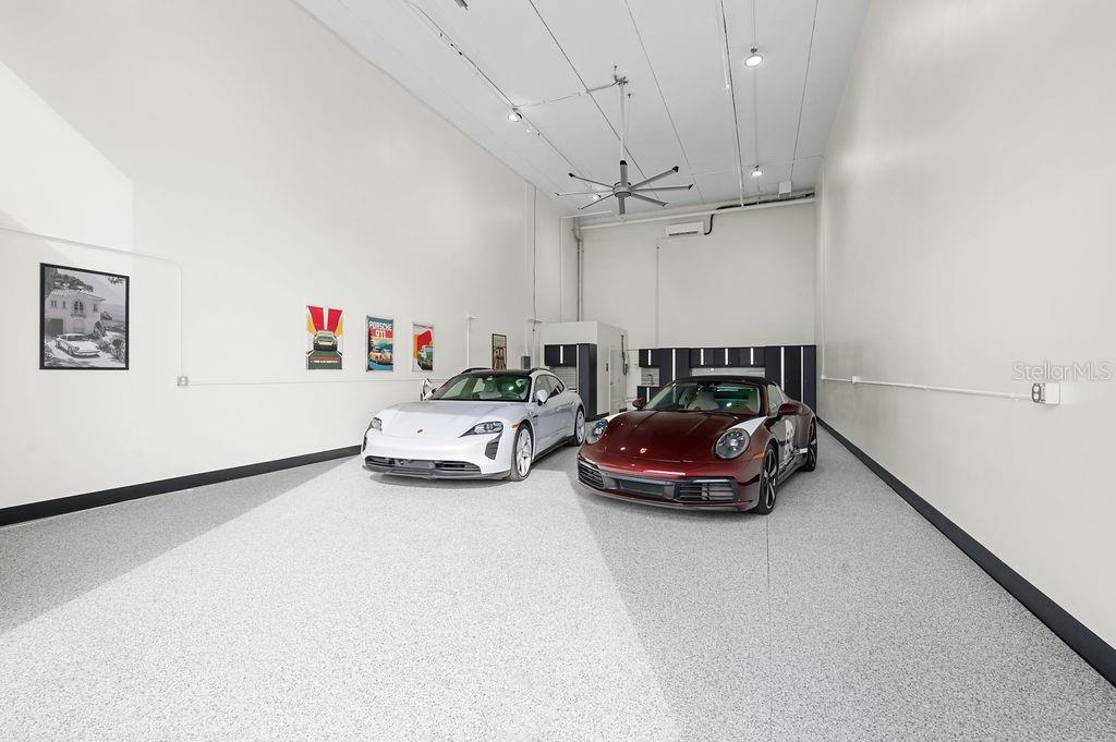 A spacious garage with white walls, epoxy flooring, and two parked Porsche sports cars — 5431 COMMUNICATIONS PARKWAY UNIT 29, LAKEWOOD RANCH, FL