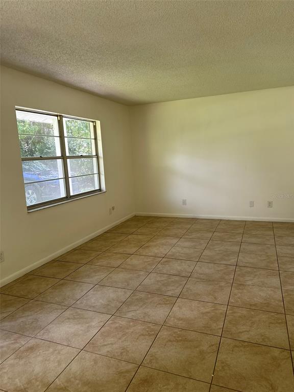 An empty room with beige tile flooring, white walls, and a large window — 2321 NE 39TH STREET, OCALA, FL