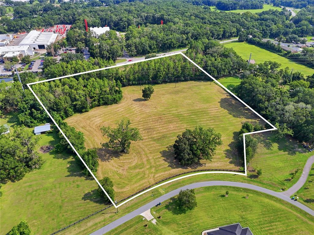 An aerial view shows a large, grassy, rectangular lot bordered by trees and a road — 14502 NW 132ND PLACE, ALACHUA, FL