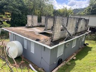 An elevated view of a gray house with an unfinished concrete block second story — Sector Titulo V BO. YAHUECAS, ADJUNTAS, PR
