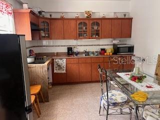A kitchen features wood cabinets, a glass-topped dining table, and a black refrigerator — Sector Titulo V BO. YAHUECAS, ADJUNTAS, PR