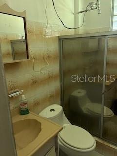 A bathroom features a vanity with a sink, a toilet, and a glass-enclosed shower — Sector Titulo V BO. YAHUECAS, ADJUNTAS, PR