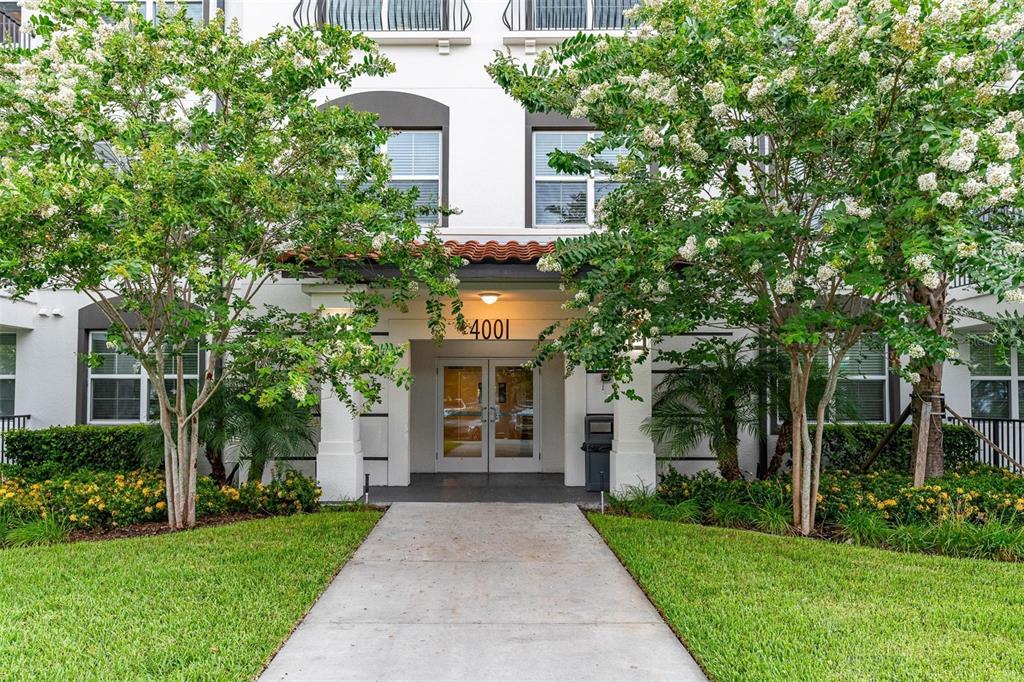 A concrete walkway leads to the entrance of a multi-story building with white walls — 4001 BREAKVIEW DRIVE UNIT D409, ORLANDO, FL
