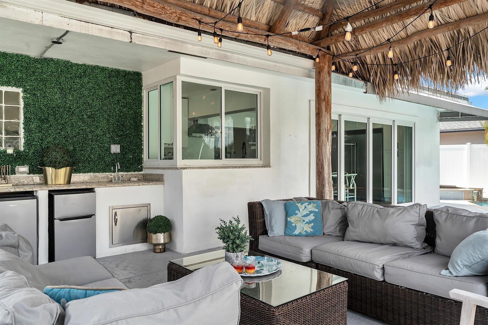An outdoor patio features a thatched roof, a kitchenette, and wicker lounge seating — 2233 SE 15th Street, Pompano Beach FL 33062, POMPANO BEACH, FL