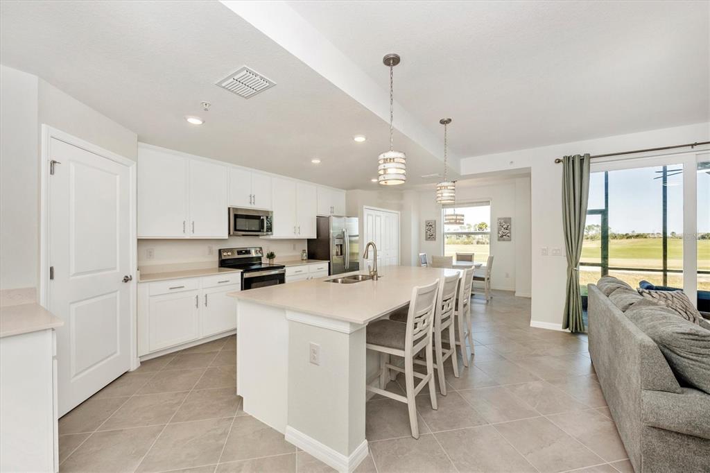 A kitchen with white cabinets, a large island, and a view of a grassy field — 12550 GALAPAGOS STREET UNIT 104, VENICE, FL