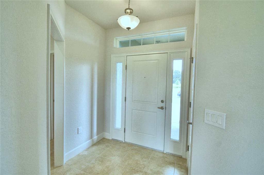 A bright entryway features a white front door with sidelights, a transom window, and tile flooring — 4624 CALAMINT LANE, AUBURNDALE, FL
