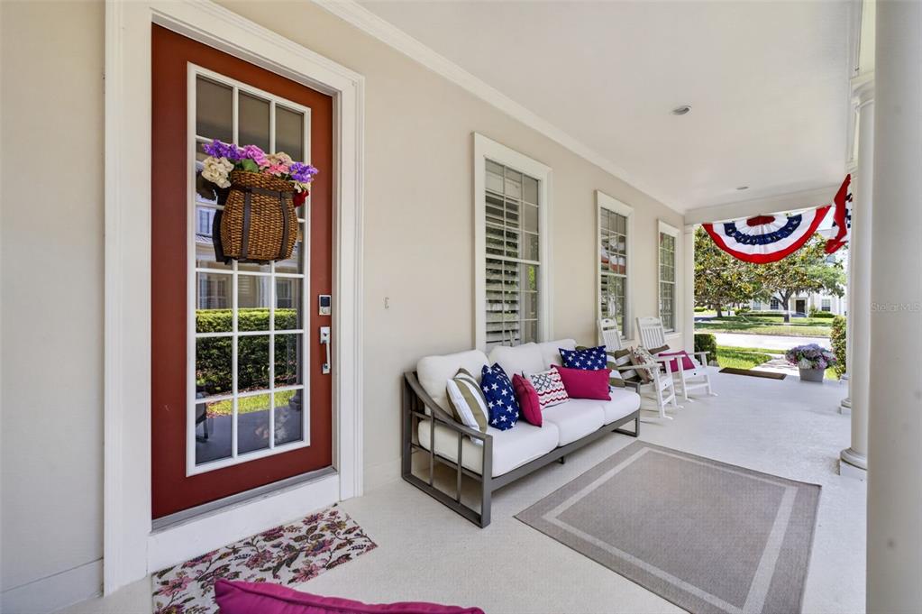 A covered front porch features a red door, white sofa with patriotic pillows, and rocking chairs — 331 CELEBRATION BOULEVARD, CELEBRATION, FL