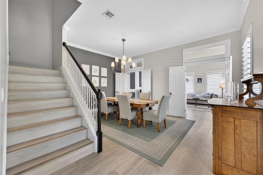 A dining room with a wooden table and chairs sits beside a staircase with white railings — 331 CELEBRATION BOULEVARD, CELEBRATION, FL