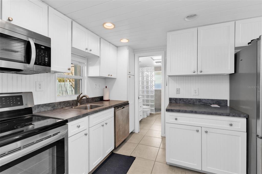 A kitchen features white cabinets, dark countertops, stainless steel appliances, and a tiled floor — 3215 PARK DRIVE, PUNTA GORDA, FL
