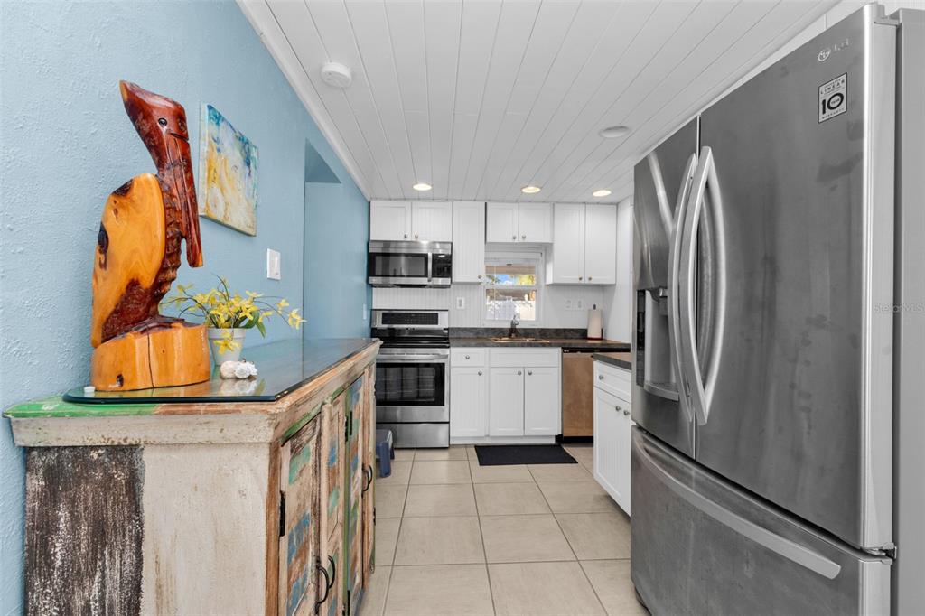 A kitchen features white cabinets, stainless steel appliances, tile flooring, and a wooden pelican sculpture — 3215 PARK DRIVE, PUNTA GORDA, FL