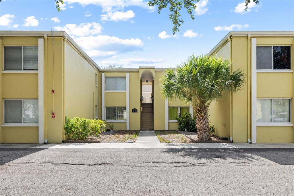 A two-story yellow apartment building features a central staircase and a palm tree in front — 3206 W AZEELE STREET UNIT 227, TAMPA, FL