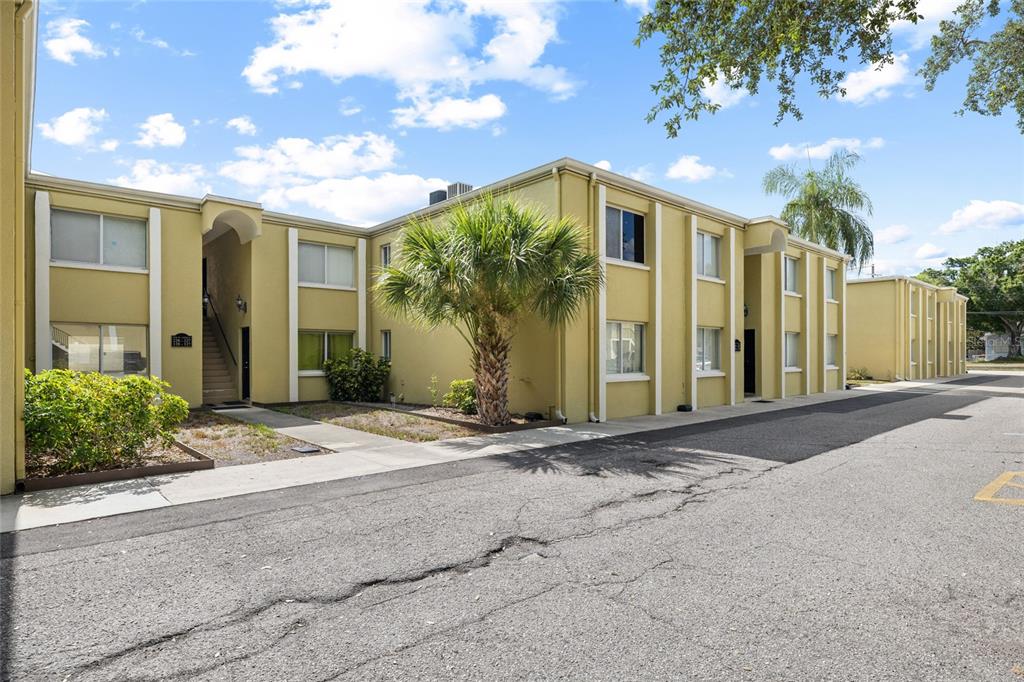 A two-story yellow apartment building with a palm tree and a paved parking lot — 3206 W AZEELE STREET UNIT 227, TAMPA, FL