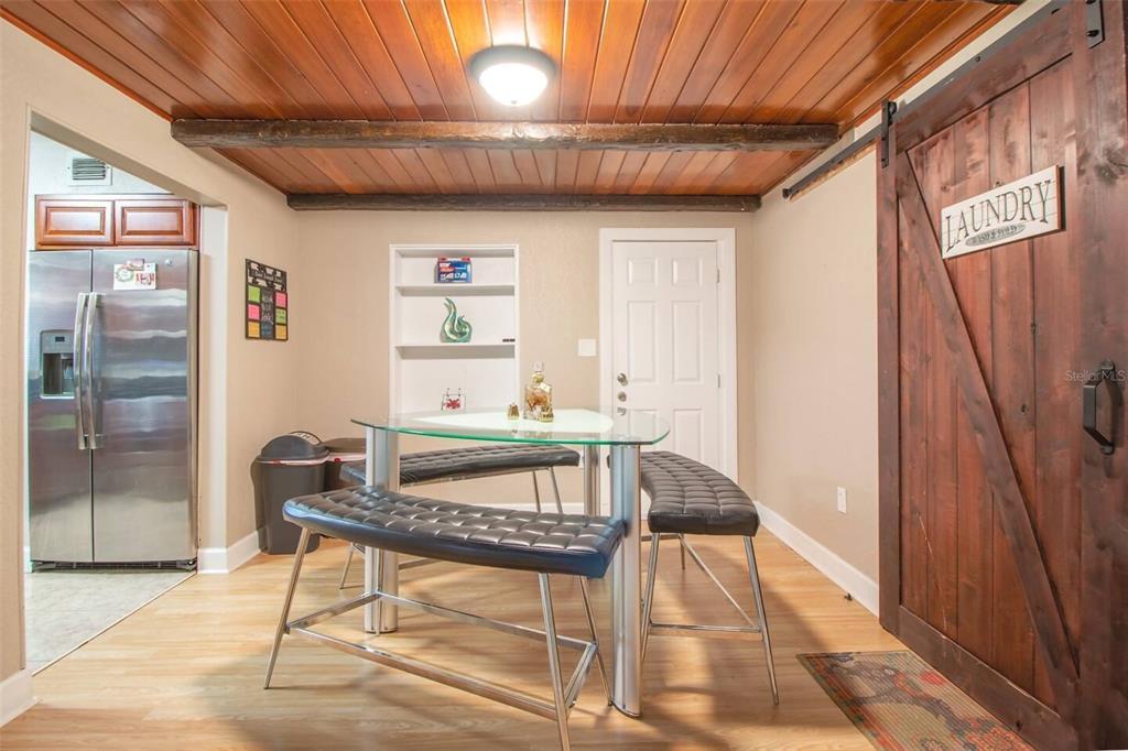 A dining area features a glass table, two black benches, wood-paneled ceiling, and sliding barn door — 1245 CATALPA LN UNIT 2, ORLANDO, FL