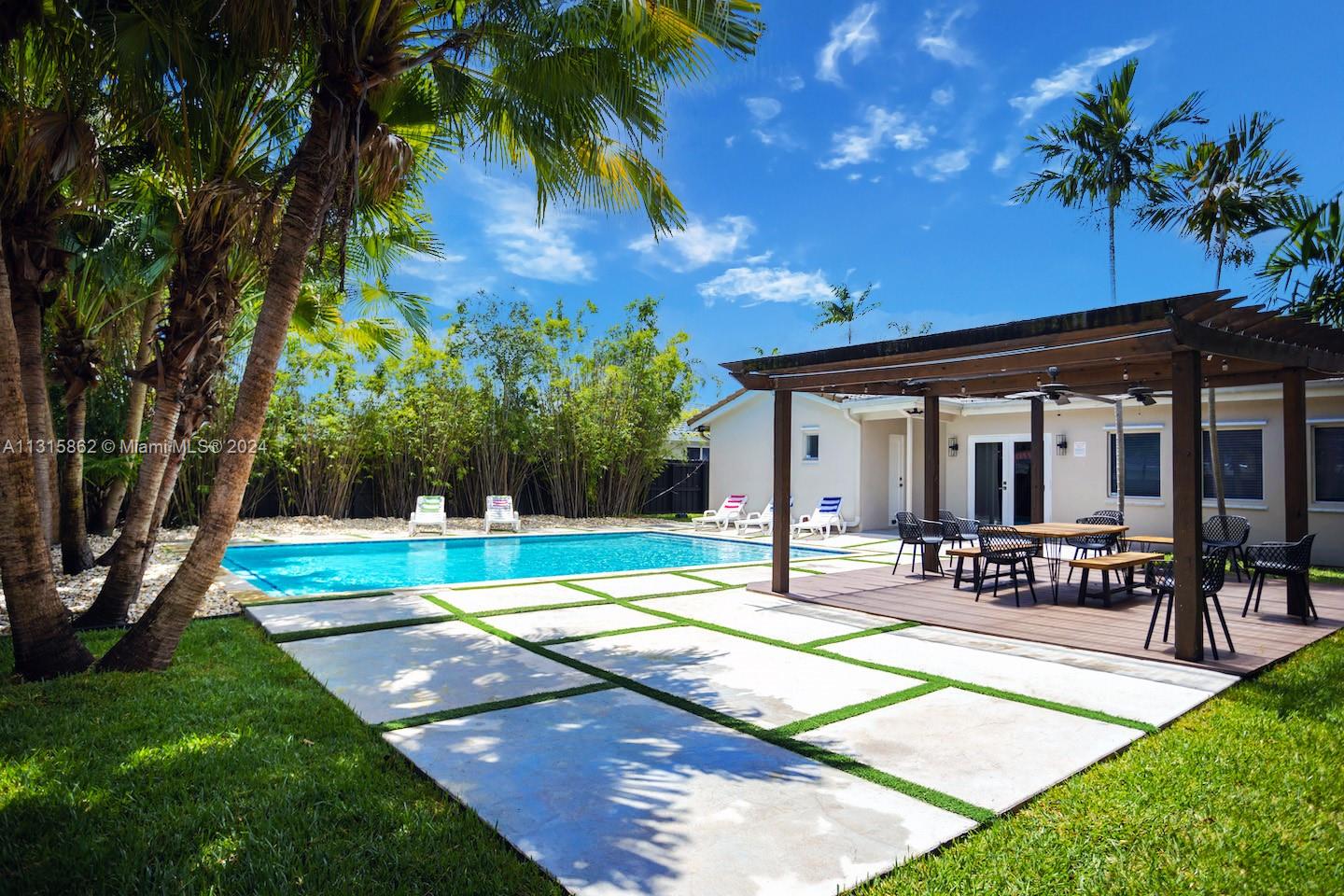 A backyard features a swimming pool, a wooden pergola over a deck, and paved patio — 1307 Rodman St, Hollywood FL 33019, HOLLYWOOD, FL