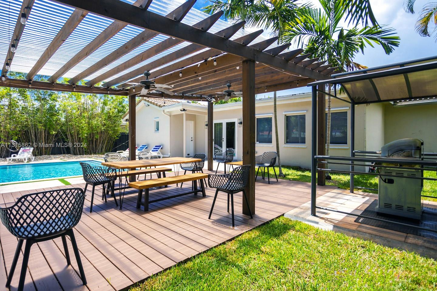 A wooden pergola covers a patio deck with outdoor dining furniture and a grill station — 1307 Rodman St, Hollywood FL 33019, HOLLYWOOD, FL