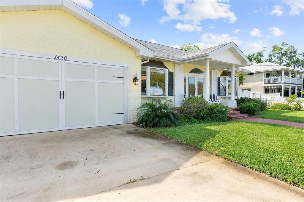 A yellow brick house features a white garage door and a front porch with columns — 1426 RIVERSIDE DRIVE, DAYTONA BEACH, FL