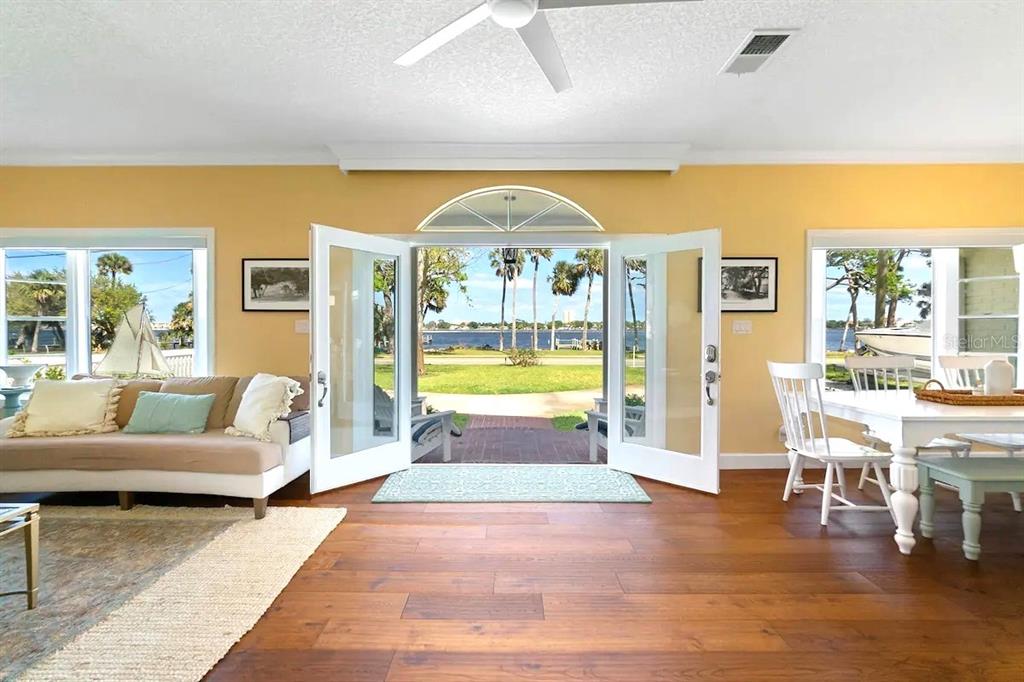 A living and dining area features hardwood floors, yellow walls, and open French doors — 1426 RIVERSIDE DRIVE, DAYTONA BEACH, FL