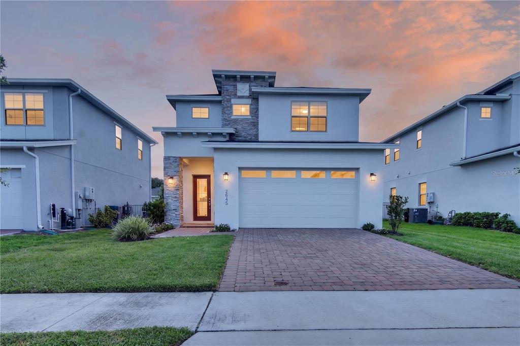 A two-story house with a stone-accented facade, a two-car garage, and a paved driveway — 2845 WILLOWSEED LANE, ST CLOUD, FL