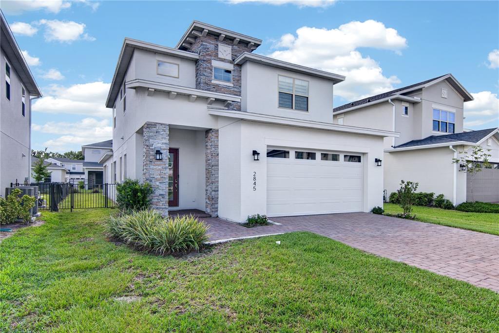 A two-story house with a stone-accented facade, a two-car garage, and a paved driveway — 2845 WILLOWSEED LANE, ST CLOUD, FL