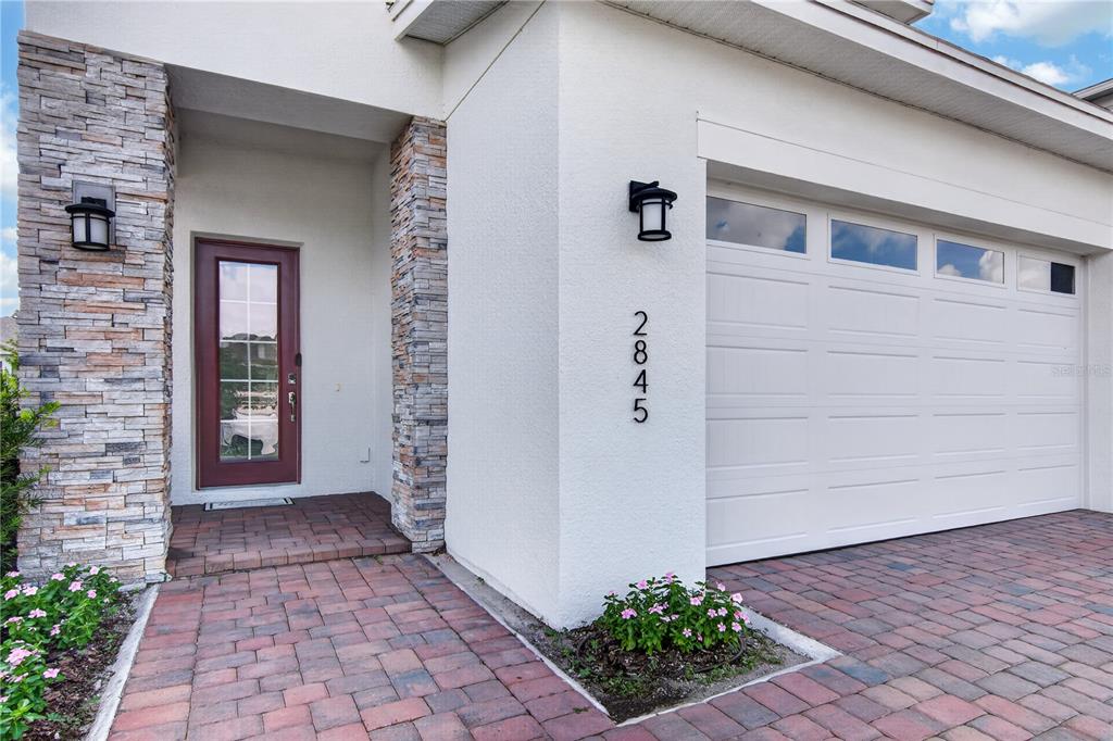 A house exterior features a brick paver driveway, a stone-accented entryway, and a white garage — 2845 WILLOWSEED LANE, ST CLOUD, FL