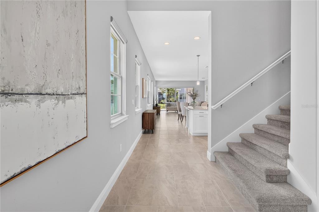 A hallway with tile flooring leads to an open kitchen and living area with stairs — 2845 WILLOWSEED LANE, ST CLOUD, FL