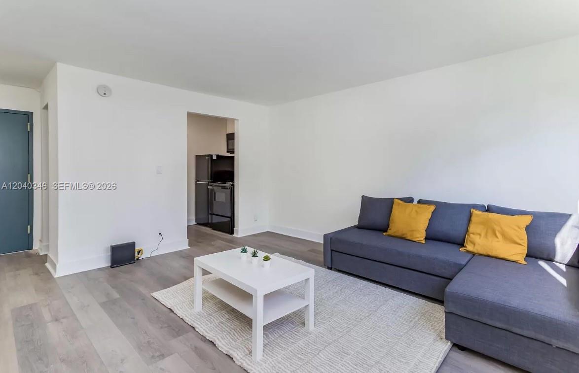 A living room features gray wood-look flooring, a blue sectional sofa, and a white coffee table — 143 SW 9th St # 301, Miami FL 33130, MIAMI, FL