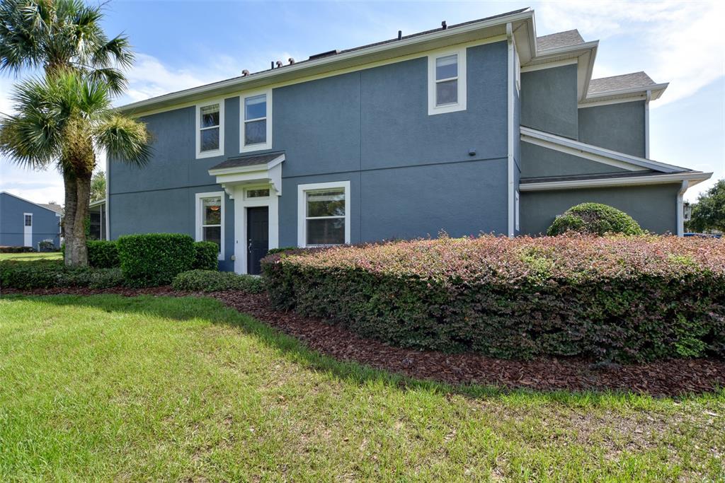 A two-story blue house features a palm tree, a front entrance, and landscaped bushes — 4178 SW 43RD CIRCLE, OCALA, FL