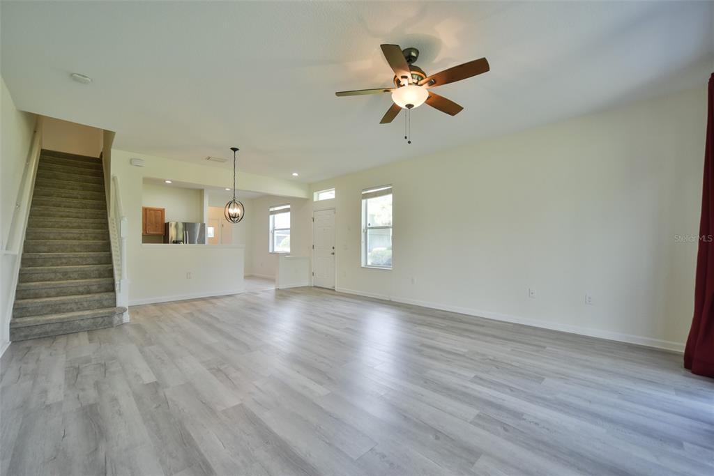 A living room with light wood-look flooring, a ceiling fan, and stairs to the left — 4178 SW 43RD CIRCLE, OCALA, FL