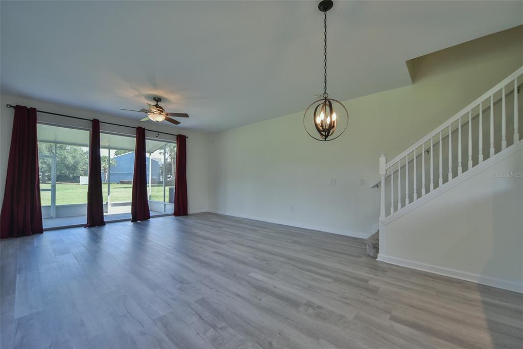 An open living area features light wood-look flooring, a ceiling fan, and a staircase — 4178 SW 43RD CIRCLE, OCALA, FL