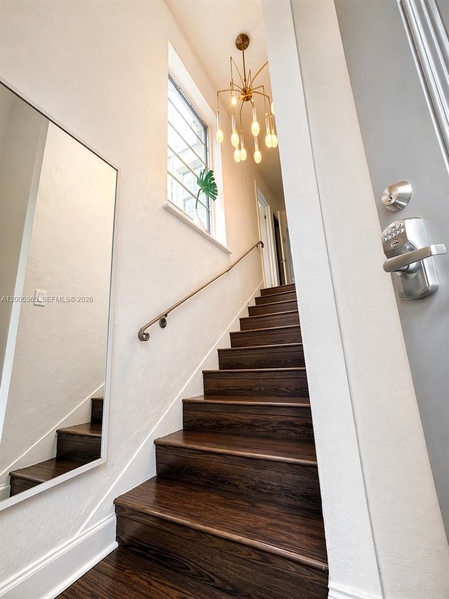 A staircase with dark wood treads leads upward past a mirror and a modern chandelier — 1005 9th St # 2, Miami Beach FL 33139, MIAMI BEACH, FL