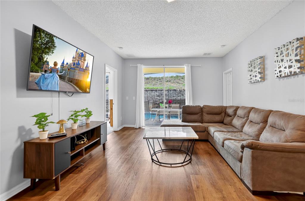 A living room features a brown sectional sofa, a television, and sliding glass doors to a pool — 258 SUNSET VIEW DRIVE, DAVENPORT, FL