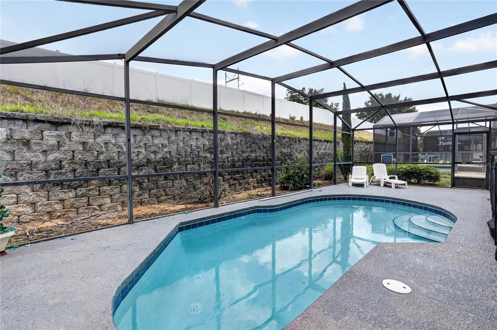 A screened-in swimming pool with a concrete deck and a stone retaining wall — 258 SUNSET VIEW DRIVE, DAVENPORT, FL