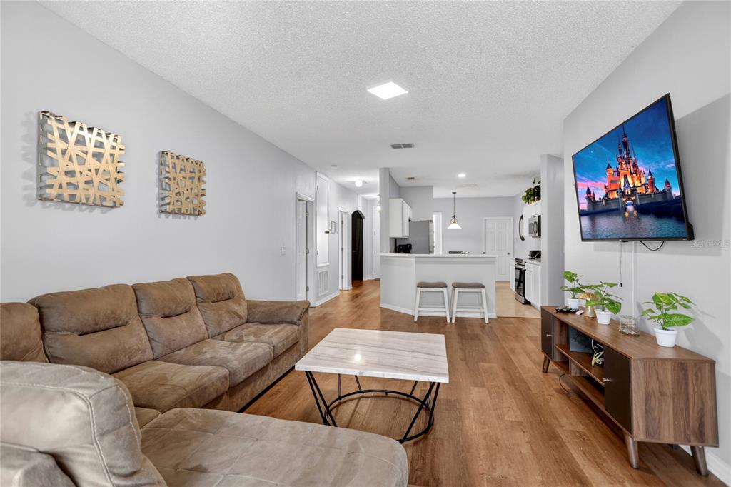 A living room features a brown sectional sofa, a marble coffee table, and a wall-mounted television — 258 SUNSET VIEW DRIVE, DAVENPORT, FL