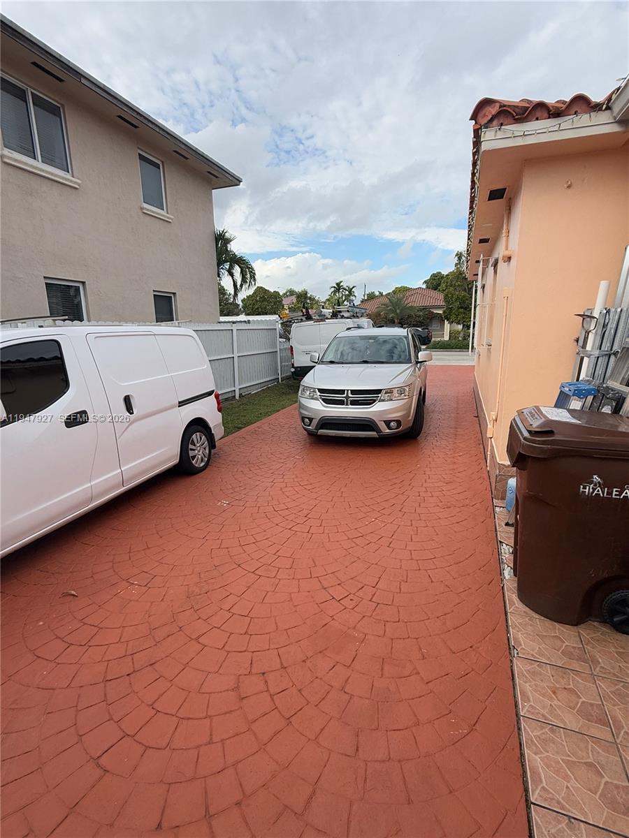 A paved driveway sits between a two-story house and a single-story home with vehicles — 380 W 41st St, Hialeah FL 33012, HIALEAH, FL