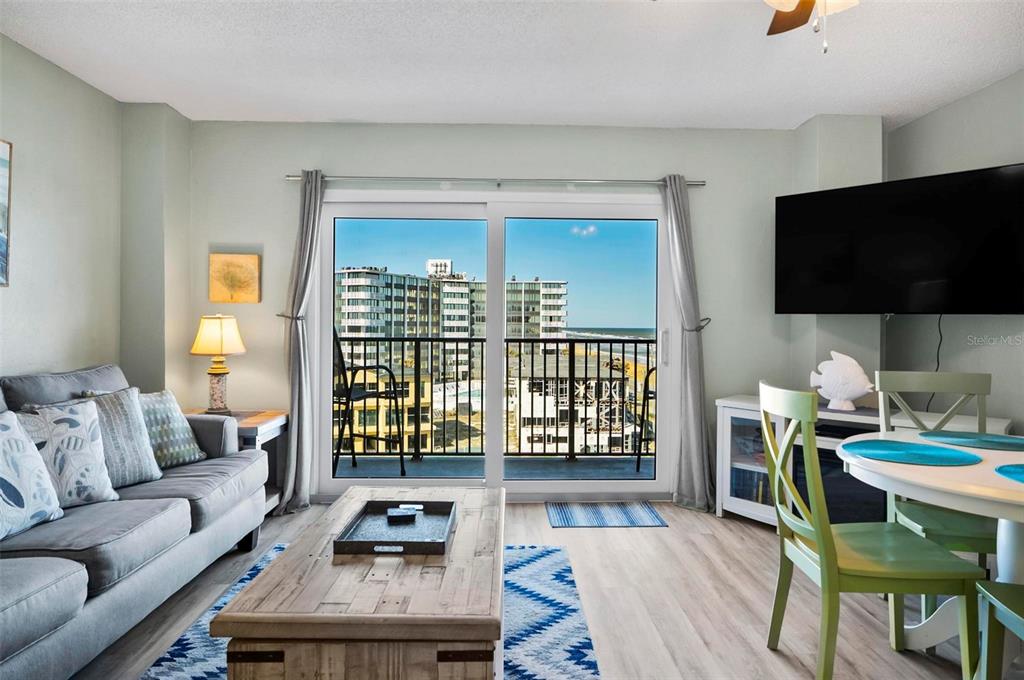 A living room with a gray sofa, wooden coffee table, and sliding doors overlooking the ocean — 3600 S OCEAN SHORE BOULEVARD UNIT 614, FLAGLER BEACH, FL