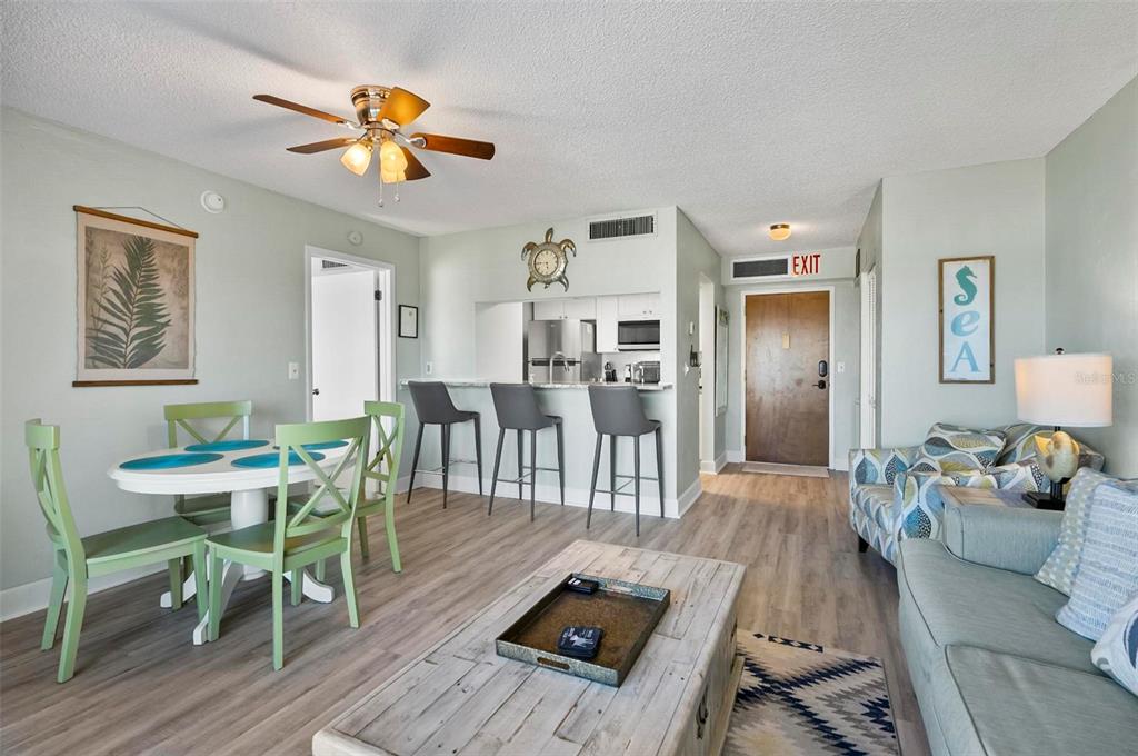 An open-concept living and dining area features light wood flooring, a breakfast bar, and furniture — 3600 S OCEAN SHORE BOULEVARD UNIT 614, FLAGLER BEACH, FL
