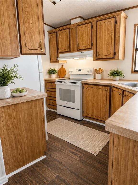 A kitchen features wood-grain cabinets, a white stove, and light-colored countertops — 1990 CRYSTAL LANE, ST CLOUD, FL