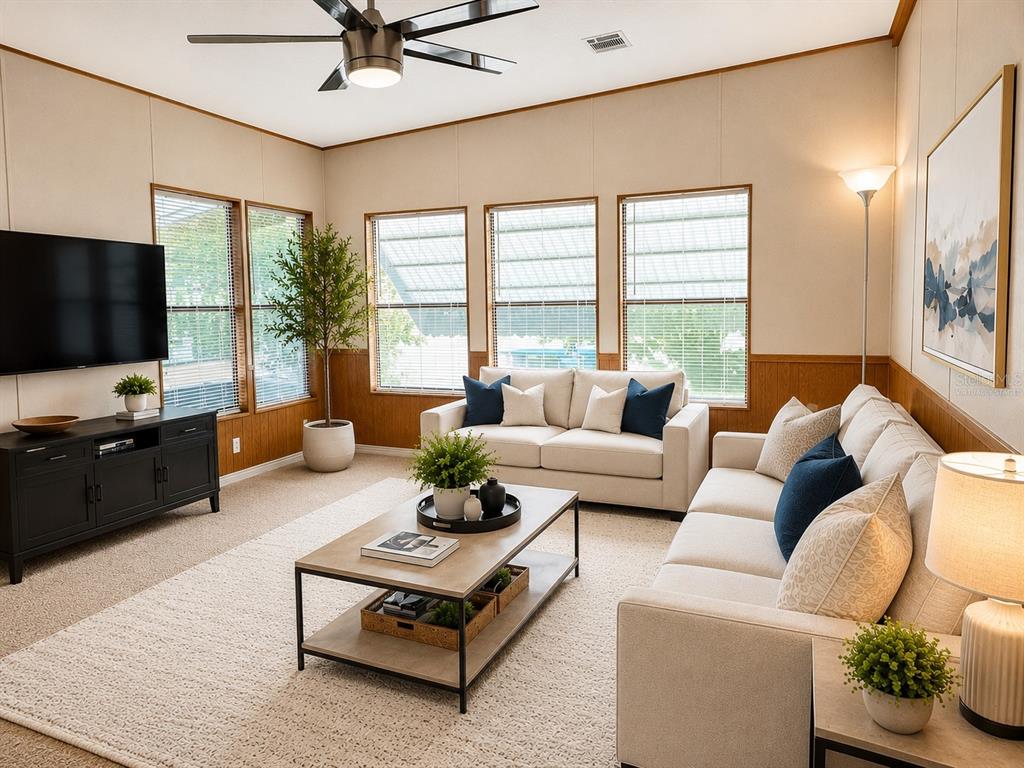 A living room features beige walls, a tan carpet, two sofas, and a television console — 1990 CRYSTAL LANE, ST CLOUD, FL