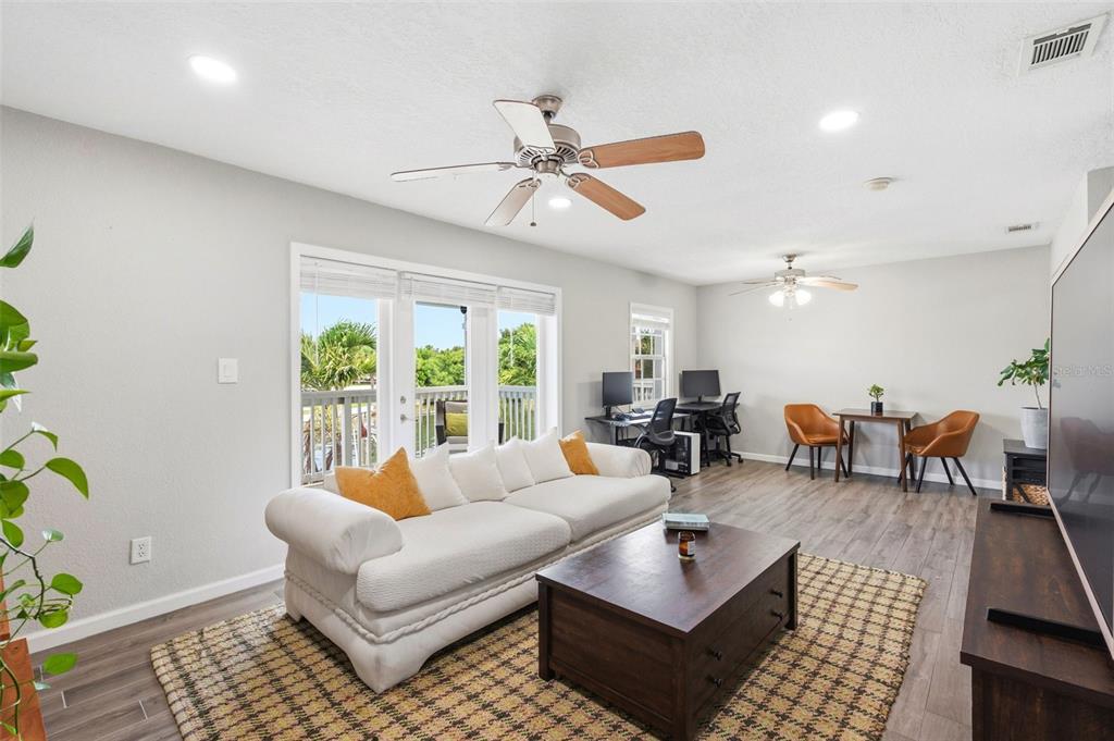 A living room features a white sofa, coffee table, desk area, and sliding glass doors — 4725 COQUINA KEY DRIVE SE UNIT D, ST PETERSBURG, FL