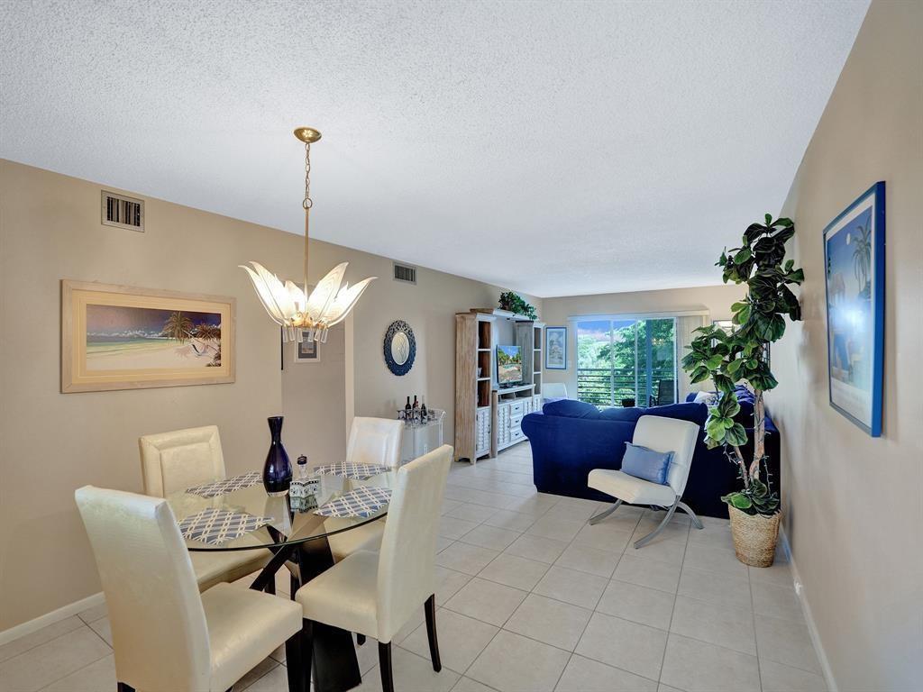 A dining area with a glass table and white chairs opens into a living room — 2003 Granada Drive # C4, Coconut Creek FL 33066, COCONUT CREEK, FL