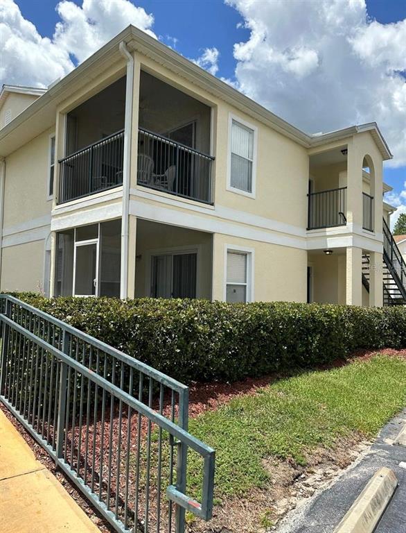A two-story apartment building features screened balconies, tan stucco siding, and a metal staircase — 8804 GRAND PALMS CIRCLE UNIT A, KISSIMMEE, FL