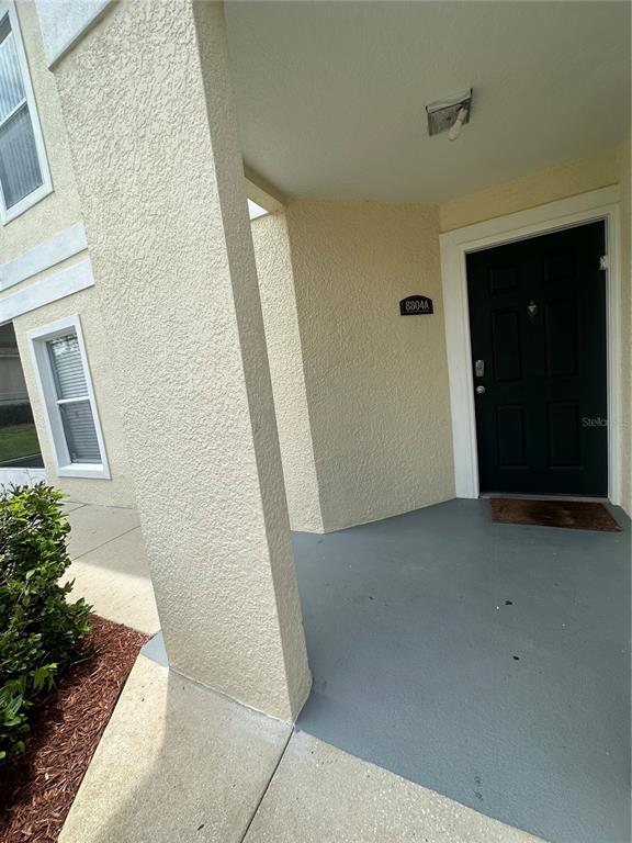 The exterior view shows a covered entryway with a dark door and a stucco wall — 8804 GRAND PALMS CIRCLE UNIT A, KISSIMMEE, FL