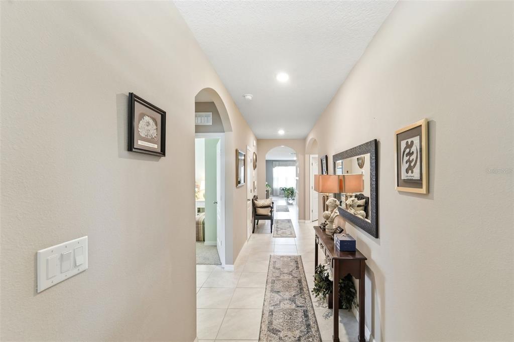 A long hallway with beige walls, tile flooring, a console table, and arched doorways — 117 RIP CORD LANE, DELAND, FL